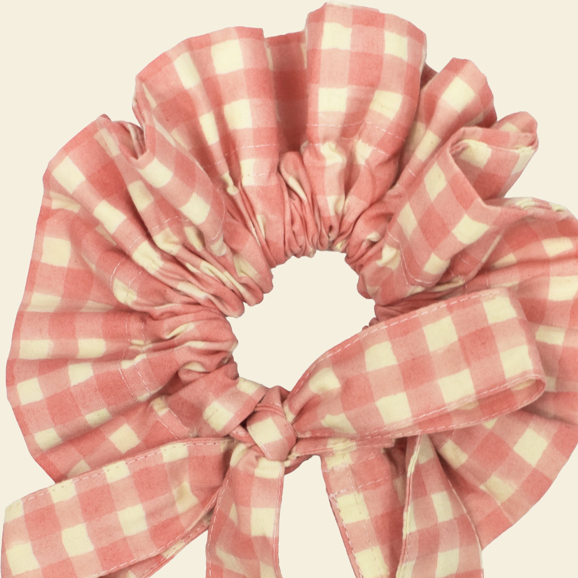 Closeup of cotton tie collar/scrunchie with ribbons printed with pink gingham pattern