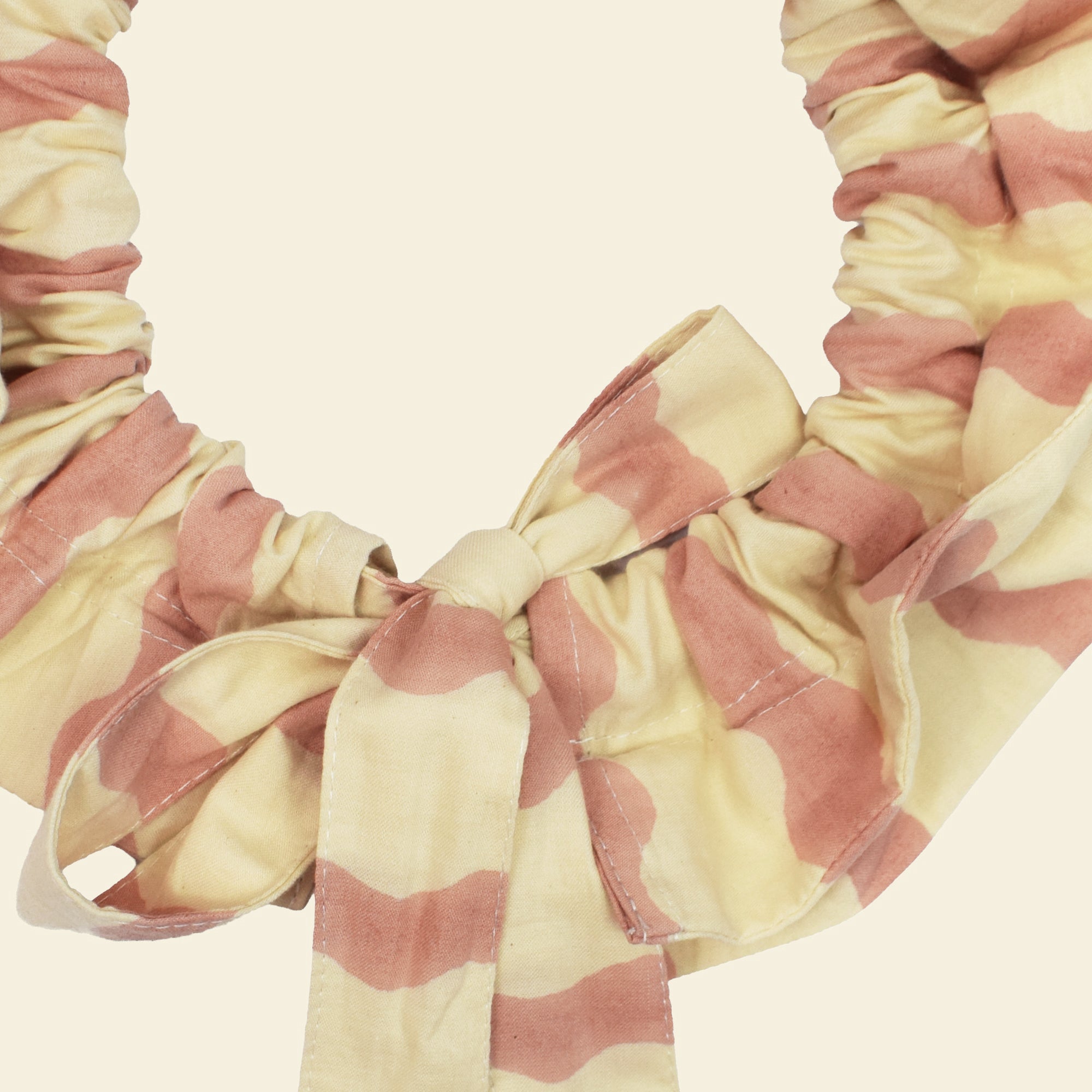 Closeup of cotton tie collar/scrunchie with ribbons printed with pink and cream striped wave pattern