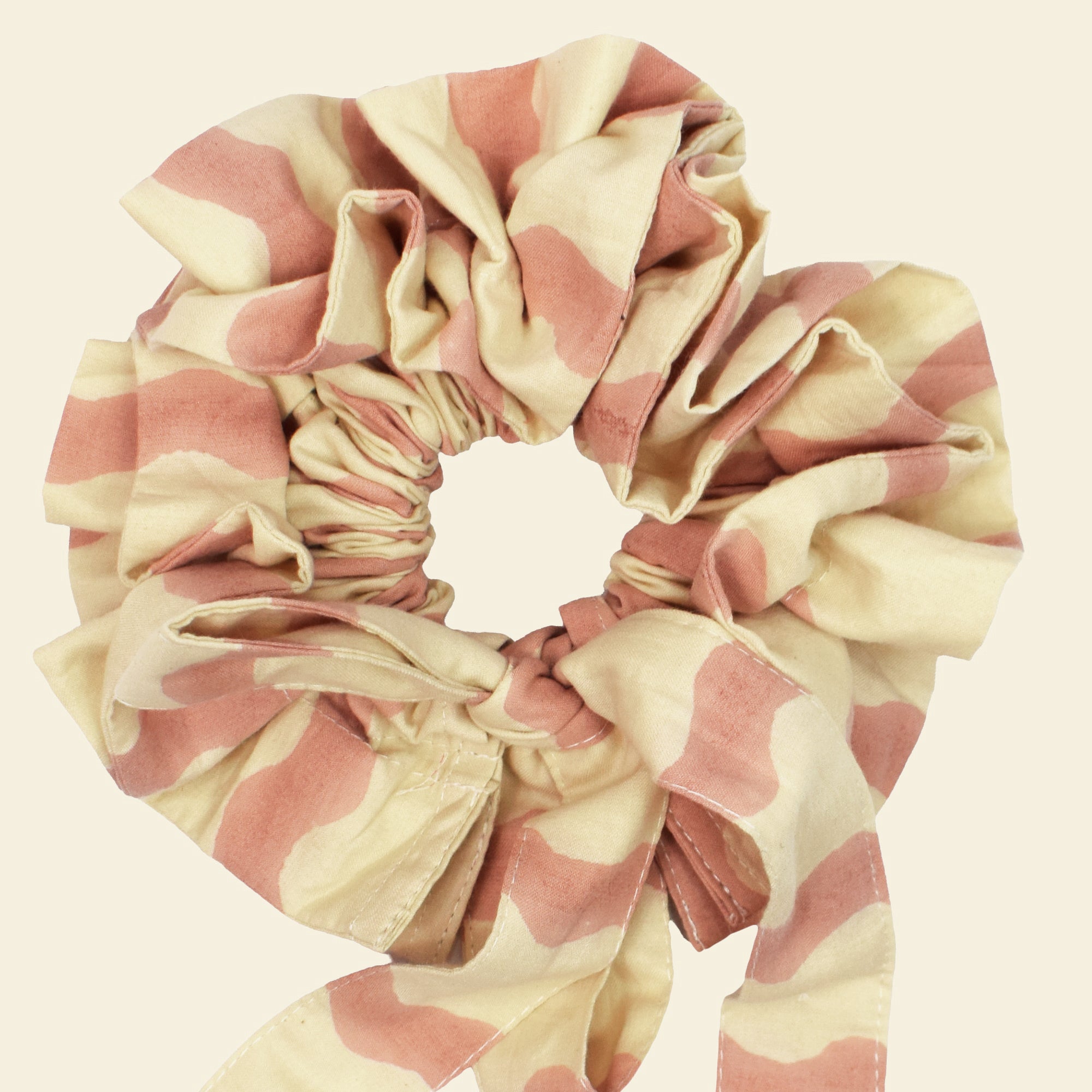 Closeup of cotton tie collar/scrunchie with ribbons printed with pink and cream striped wave pattern