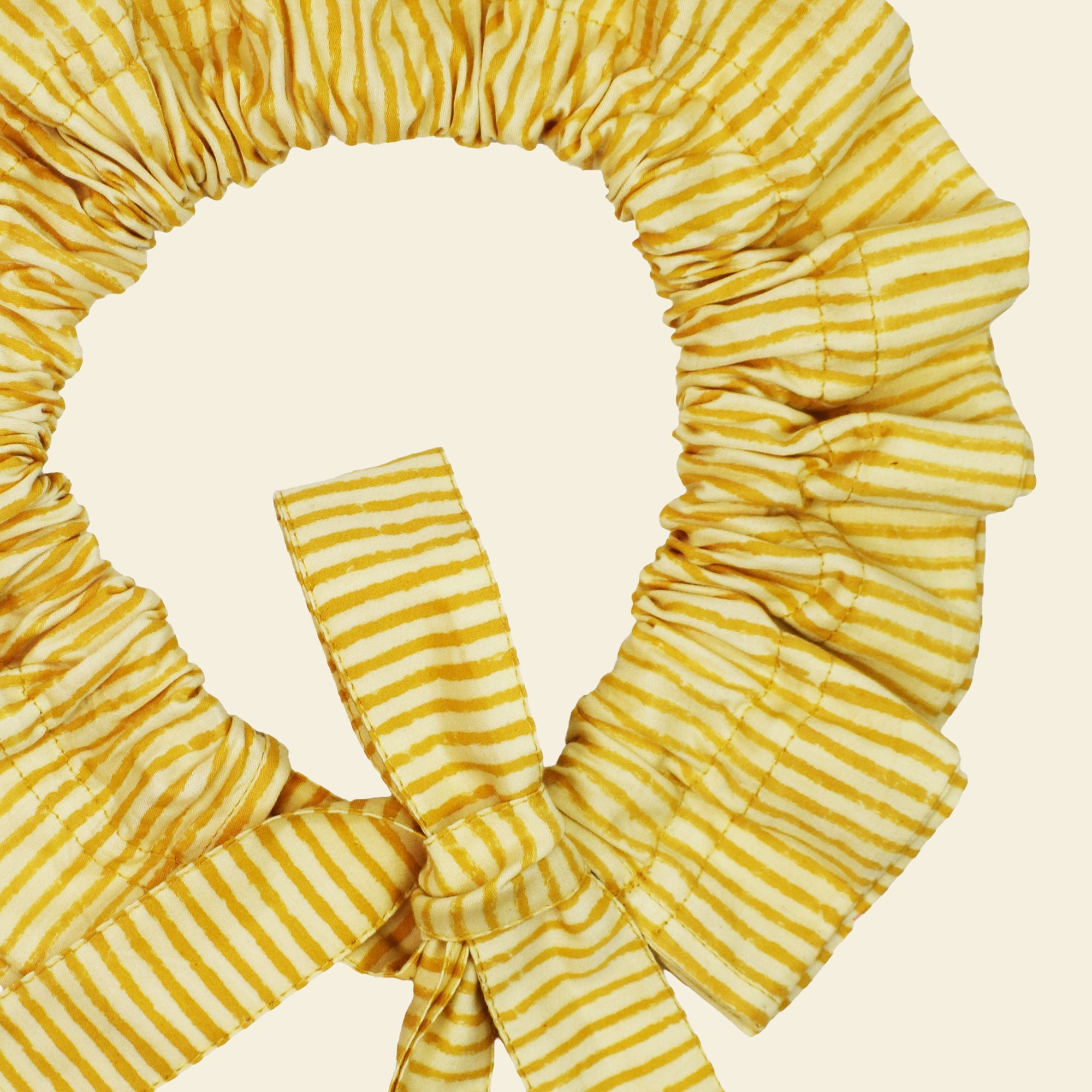 Closeup of cotton tie collar/scrunchie with ribbons printed with yellow striped pattern
