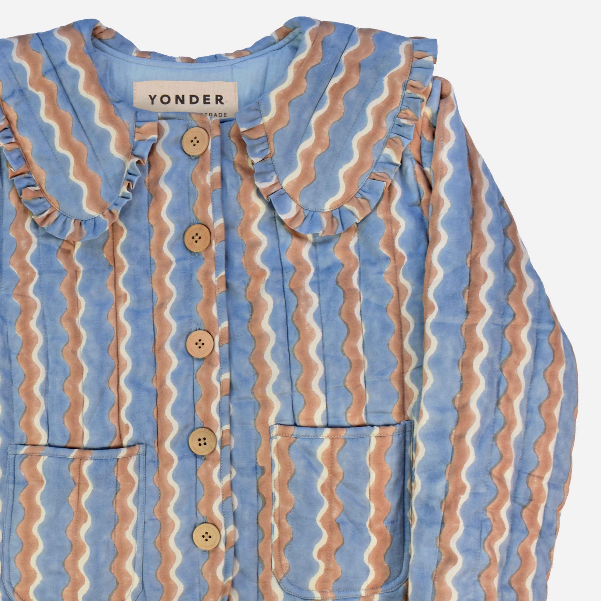 Closeup of cotton quilted jacket printed with blue and brown striped wave pattern and frill collar