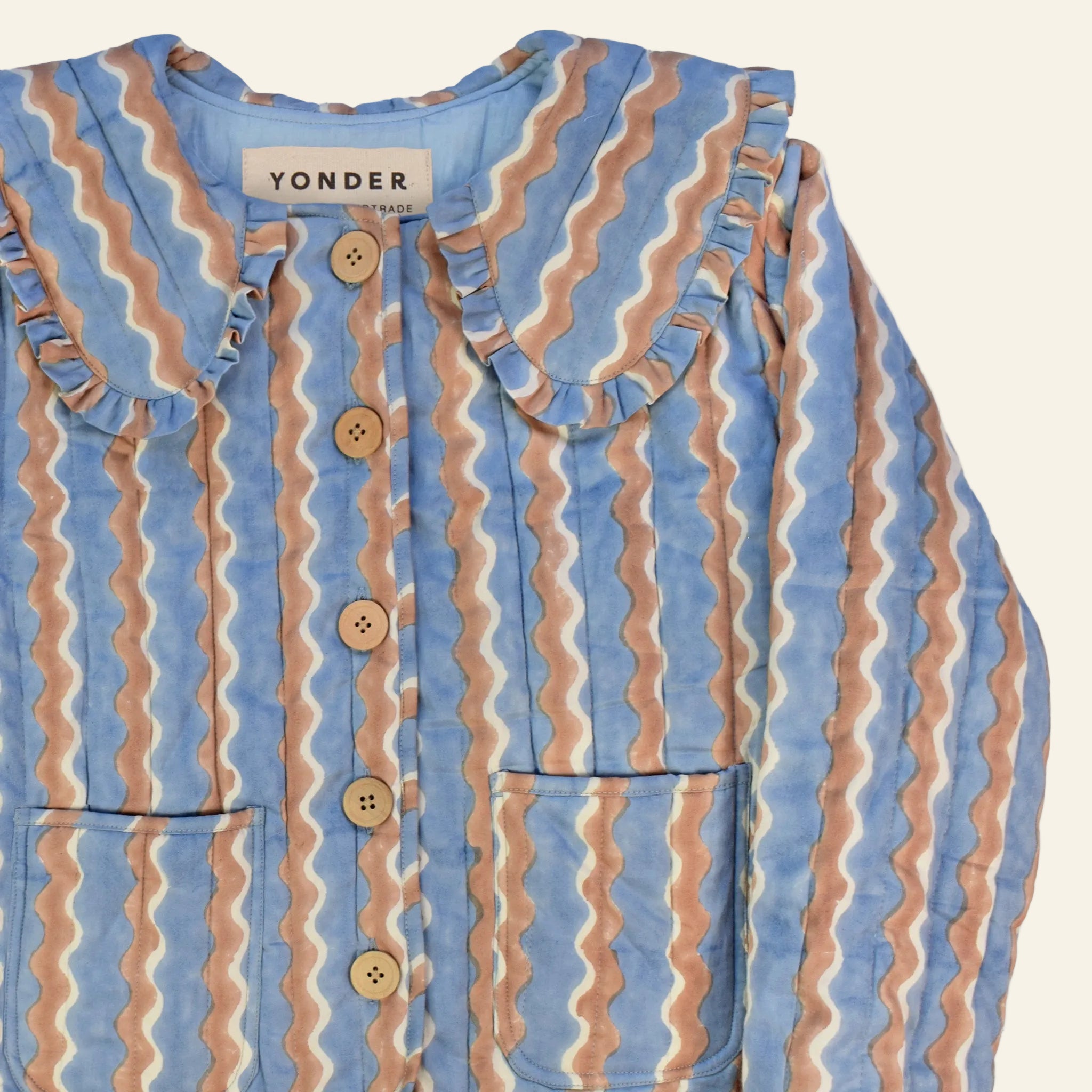 Closeup of cotton quilted jacket printed with blue and brown striped wave pattern and frill collar