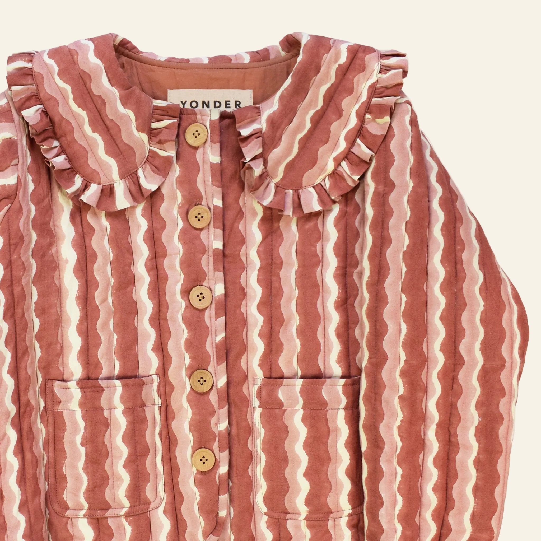Closeup of cotton quilted jacket printed with pink striped wave pattern and frill collar