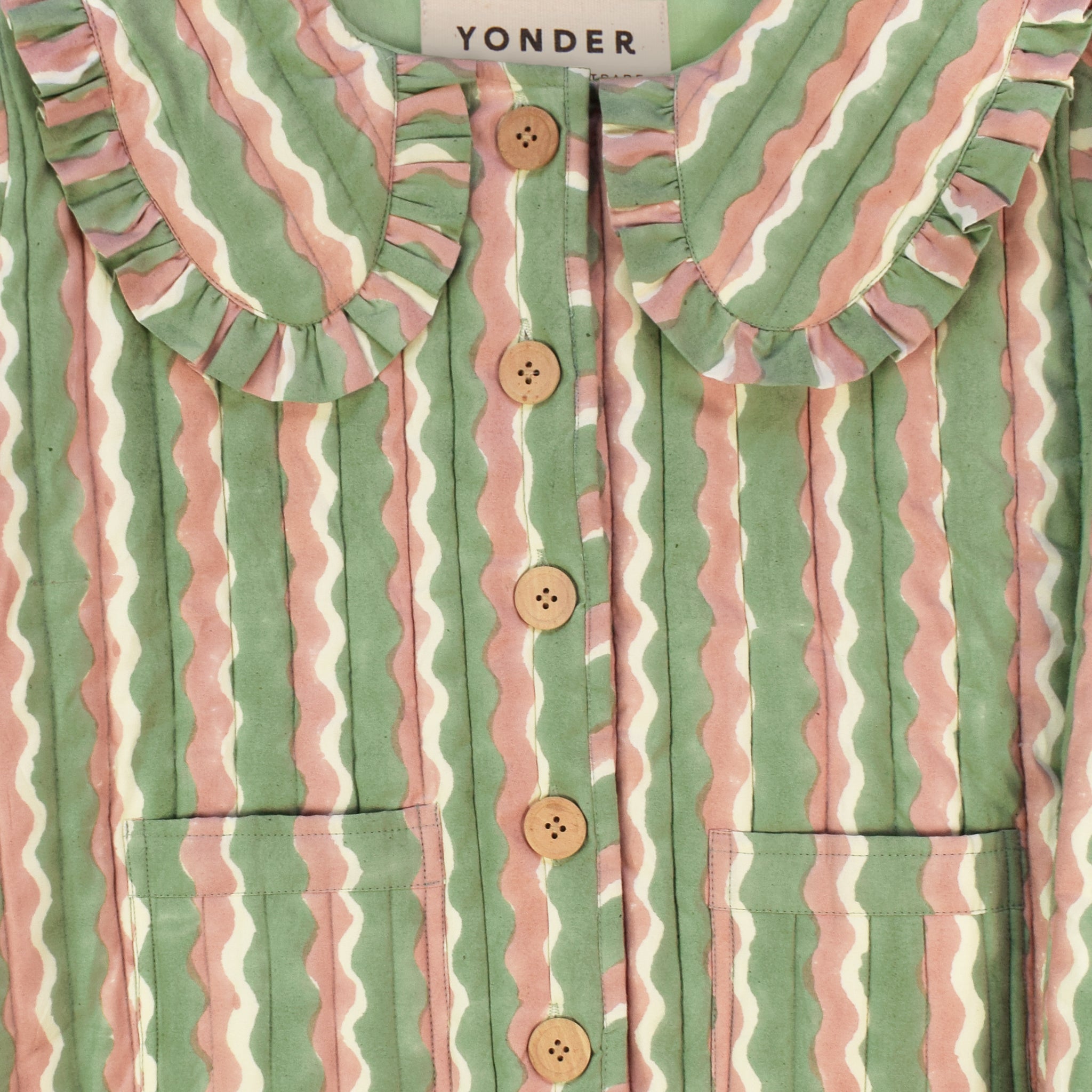 Closeup of cotton quilted jacket printed with mint green and pink striped wave pattern and frill collar