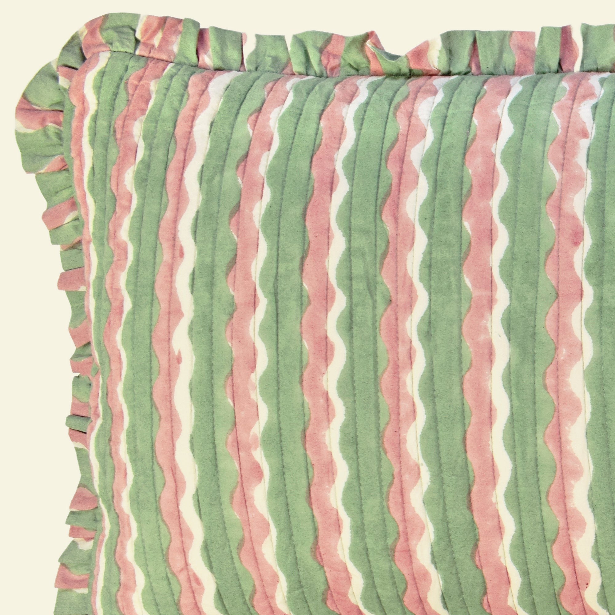 Close-up of Yonder Living Whirly mint bolster quilted frill cushion, sage green and rose block-printed wave and frilled edge