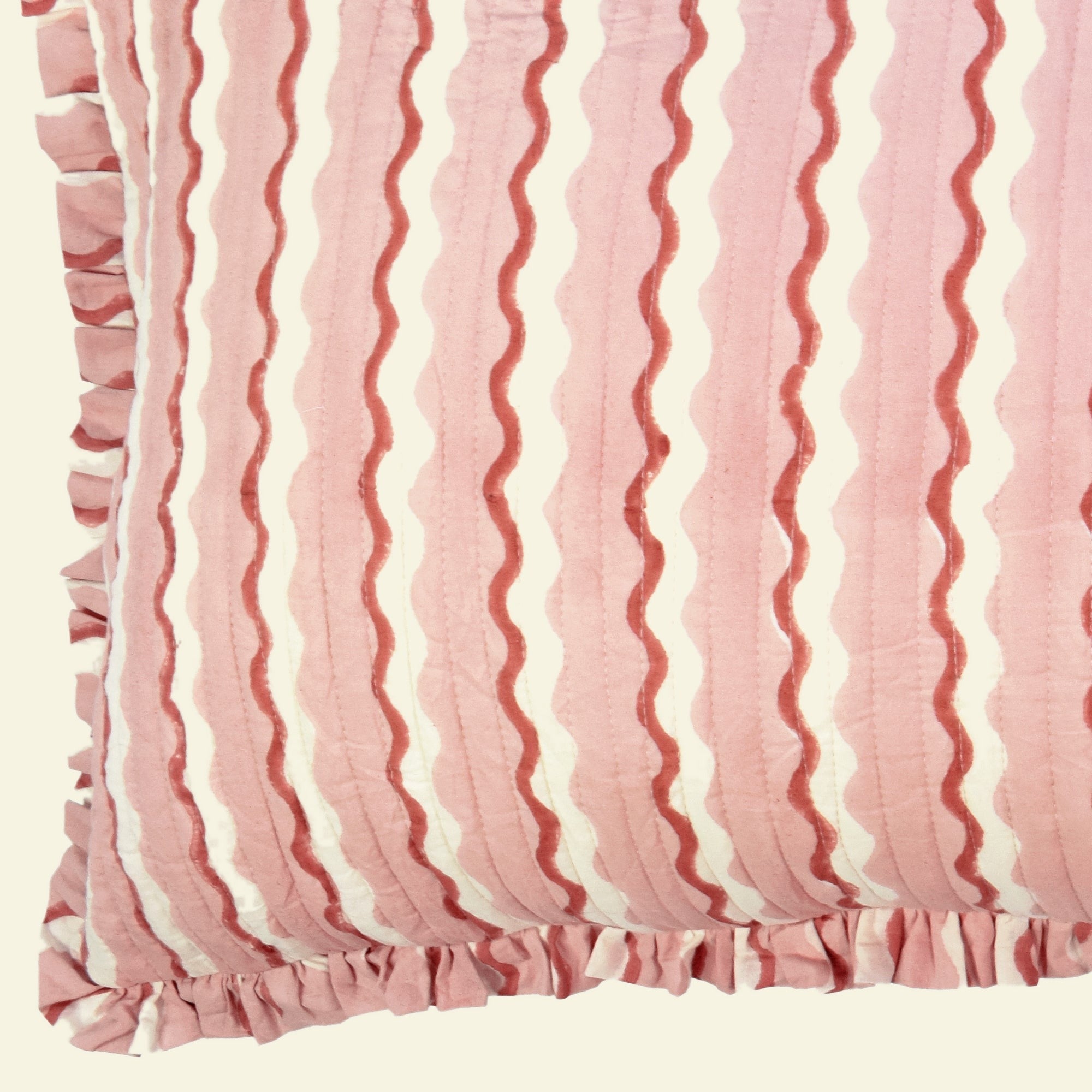 Close-up of Yonder Living Wiggle floss bolster quilted frill cushion, blush pink block-printed wave and frilled edge