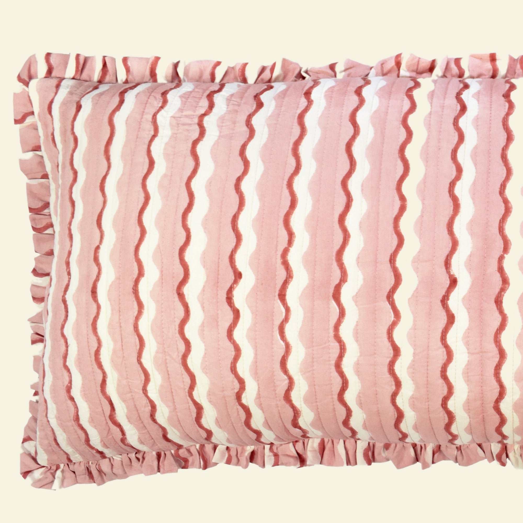 Close-up of Yonder Living Wiggle floss bolster quilted frill cushion, blush pink block-printed wave and frilled edge