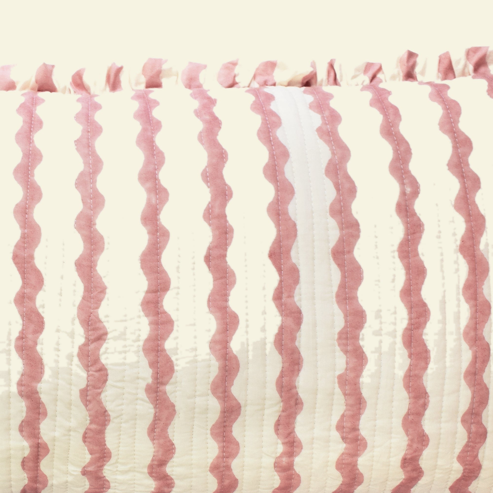 Close-up of Yonder Living Ripple ice cream bolster quilted frill cushion, soft rose block-printed ripple and frilled edge