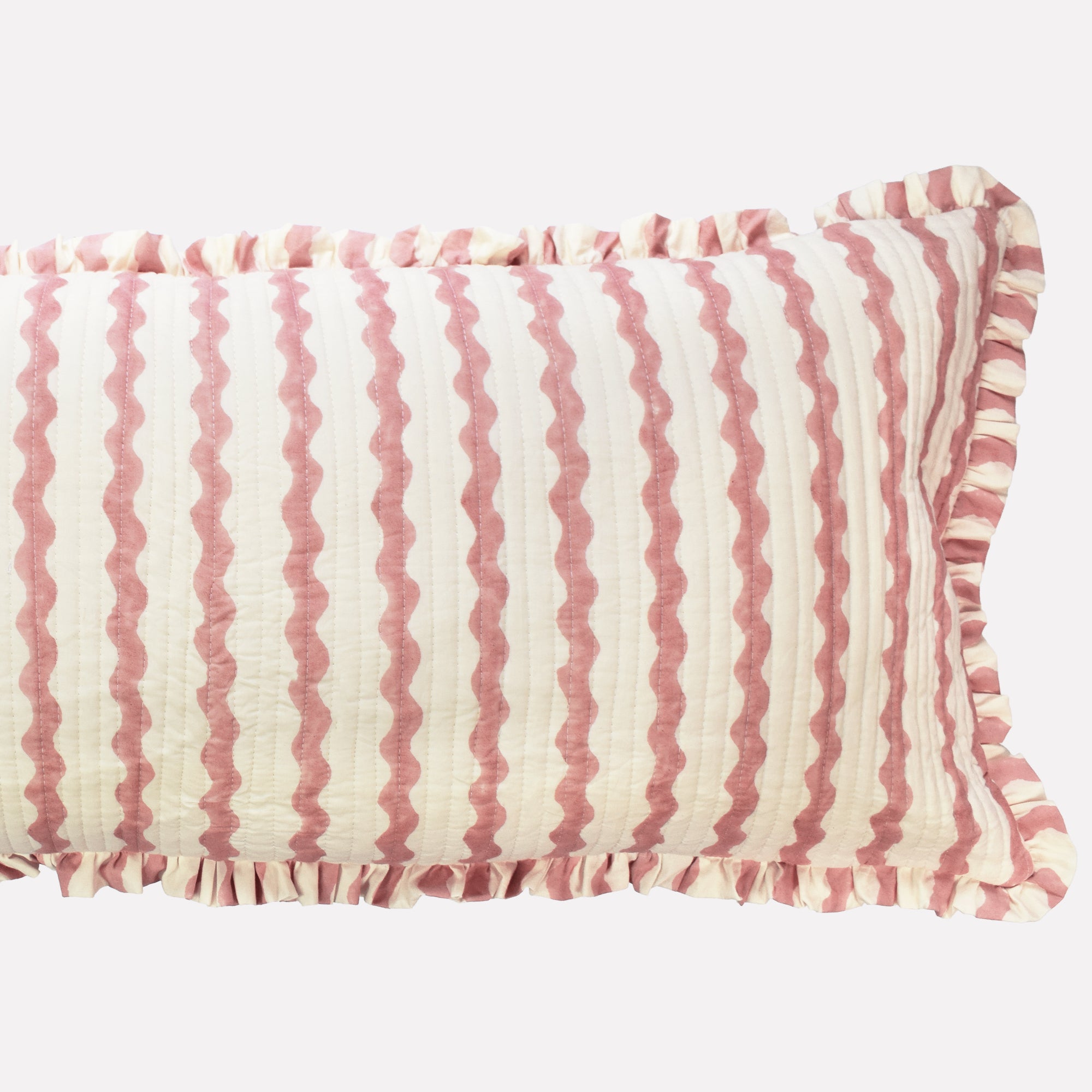 Closeup of long cotton quilted cushion printed with pink and white striped wave pattern and frill border