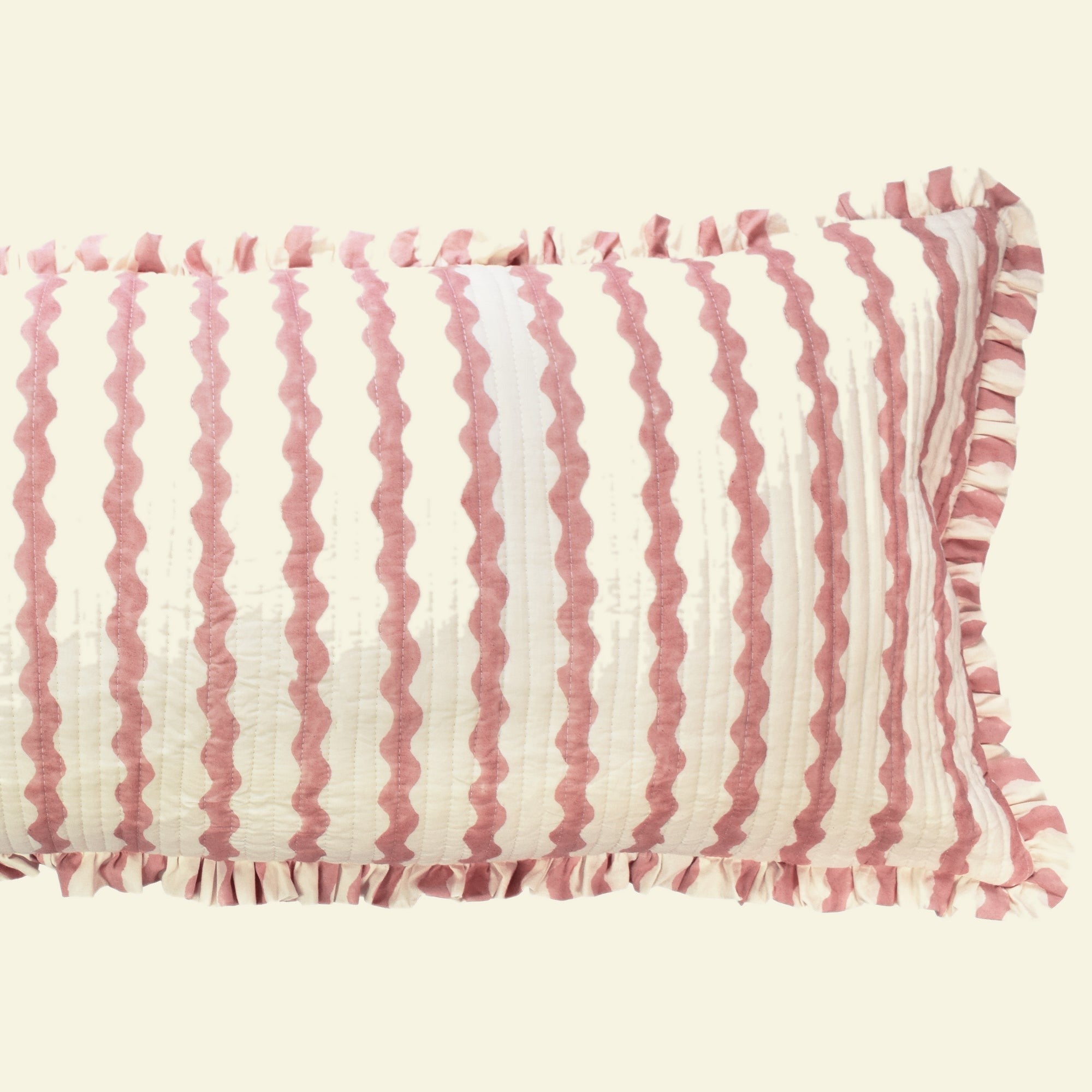 Close-up of Yonder Living Ripple ice cream bolster quilted frill cushion, soft rose block-printed ripple and frilled edge