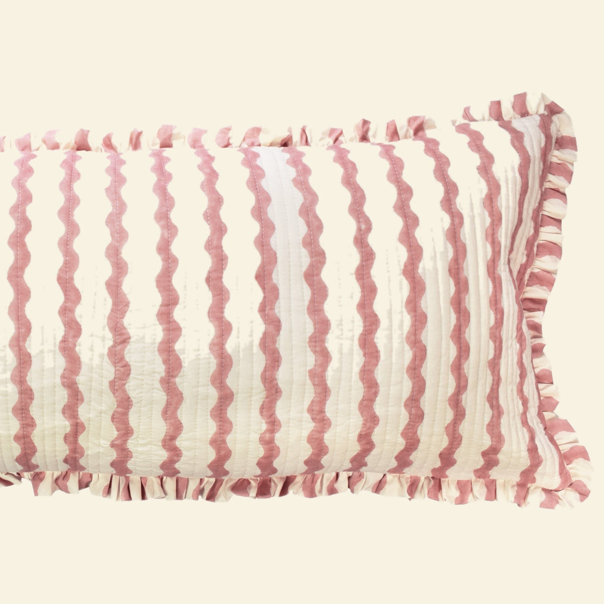 Close-up of Yonder Living Ripple ice cream bolster quilted frill cushion, soft rose block-printed ripple and frilled edge