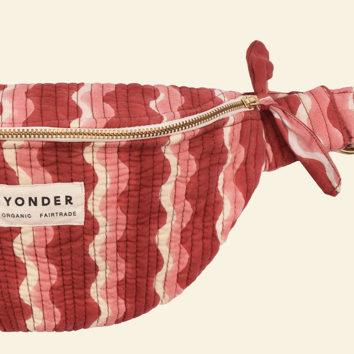 Close-up of Yonder berry-jam whirly bum bag, quilted organic cotton with brass zip, hand block-printed