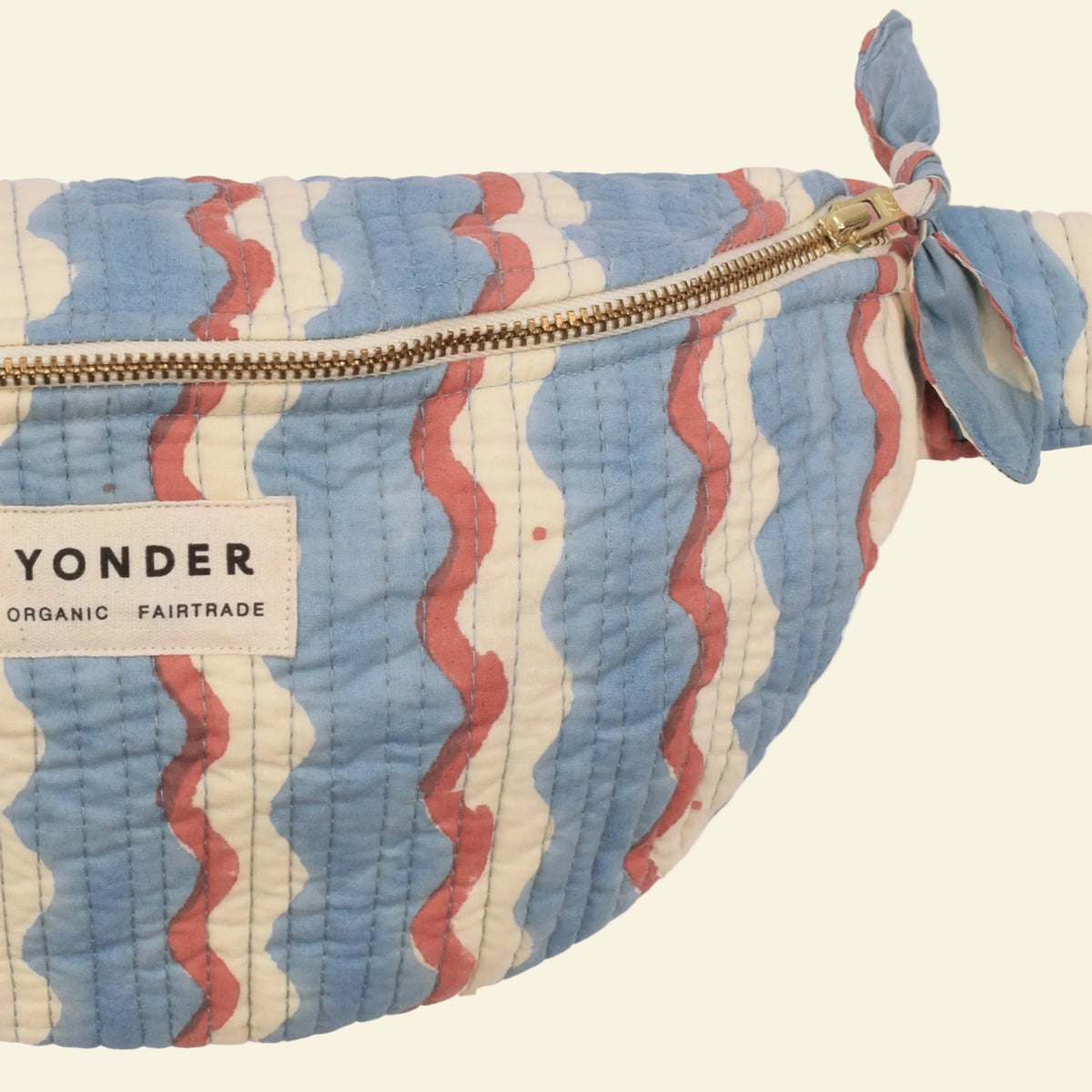 Close-up of Yonder sky-blue wiggle bum bag, quilted organic cotton with brass zip, hand block-printed