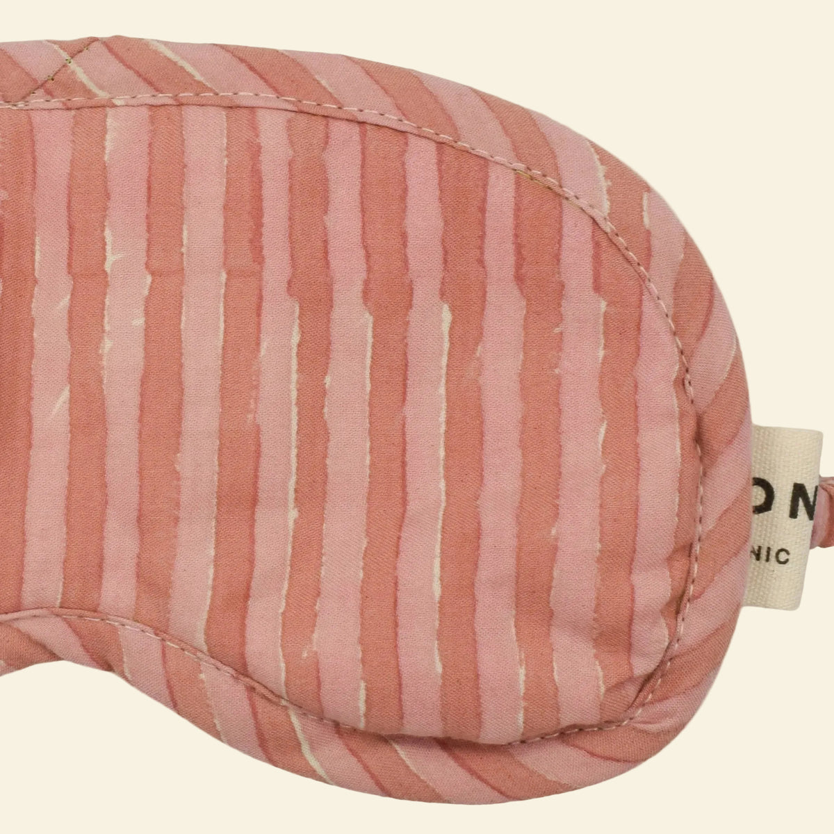 Close-up of Yonder Rhubarb eye mask showing the pink hand block-printed candy stripe