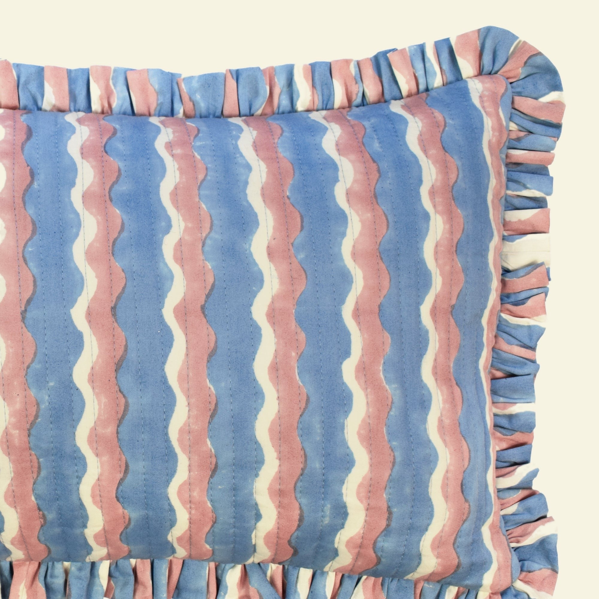 Close-up of Yonder Living Whirly blueberry quilted frill cushion, cool blue block-printed wave and frilled edge