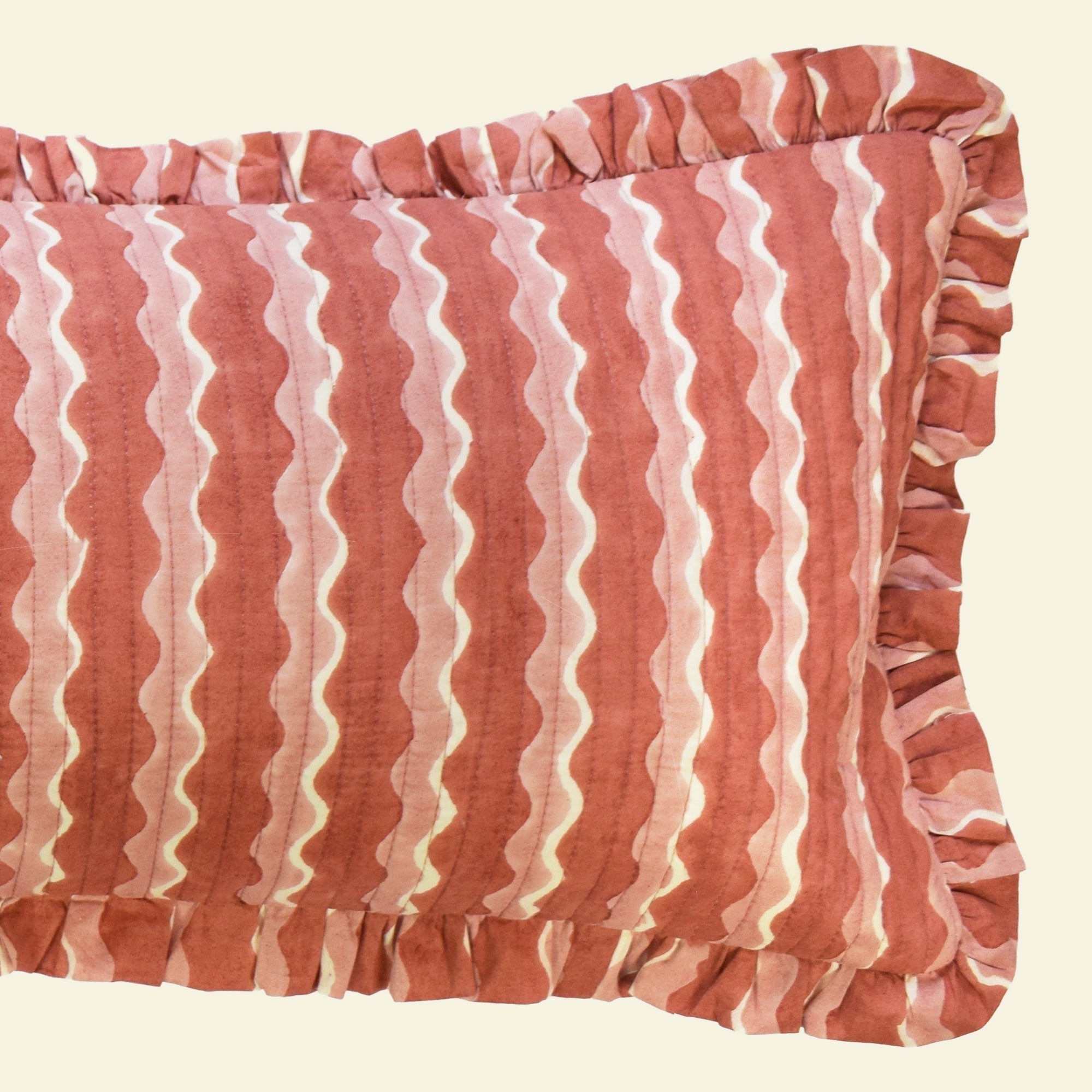 Close-up of Yonder Living Whirly ginger bolster quilted frill cushion, warm ginger block-printed wave and frilled edge