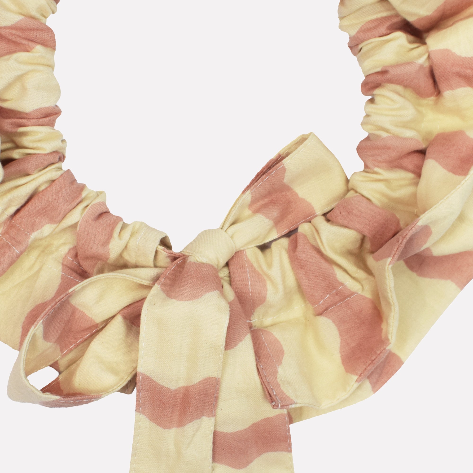 Closeup of cotton tie collar/scrunchie with ribbons printed with pink and cream striped wave pattern