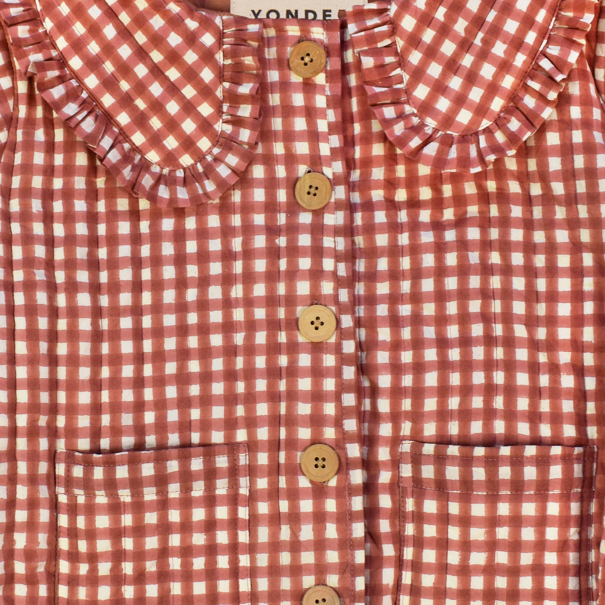 Closeup of cotton quilted jacket printed with red gingham pattern and frill collar