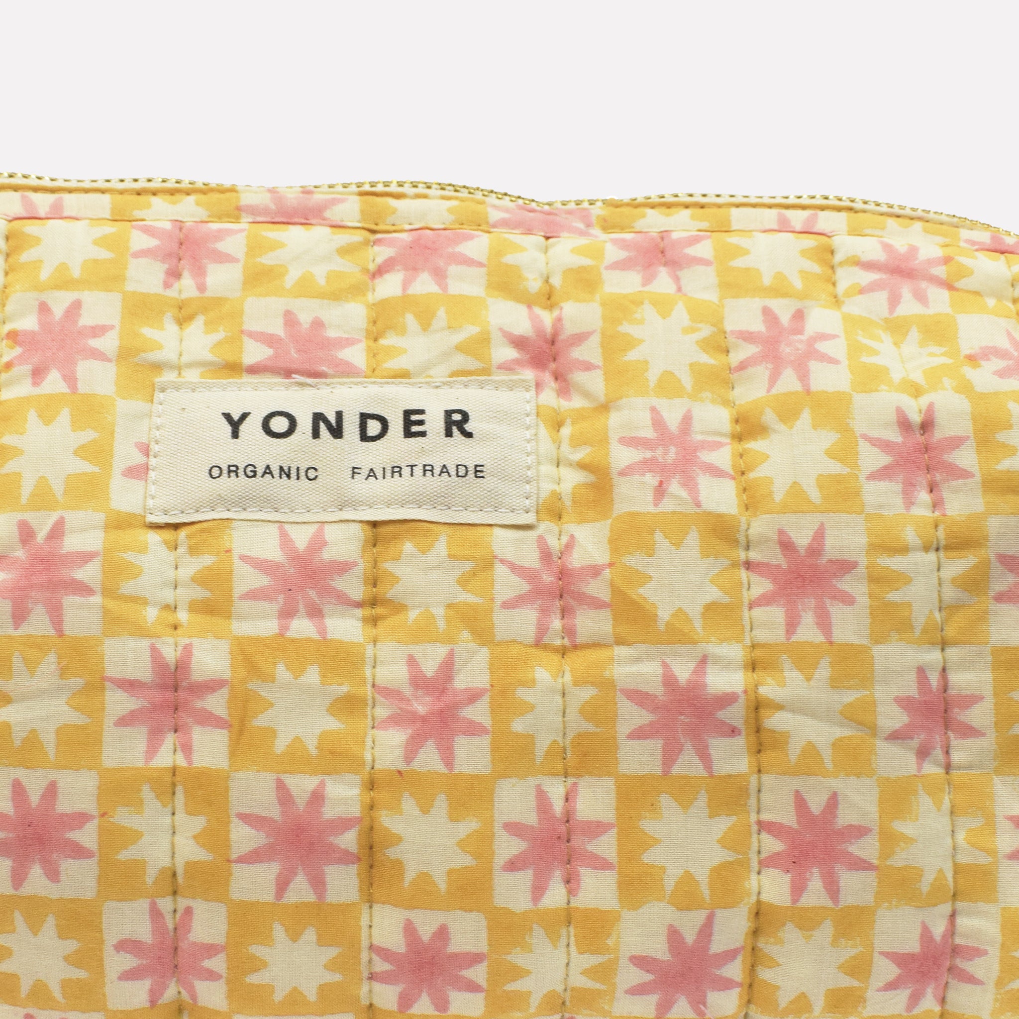 Closeup of cotton quilted wash/toiletry bag printed with yellow, pink, and white star pattern