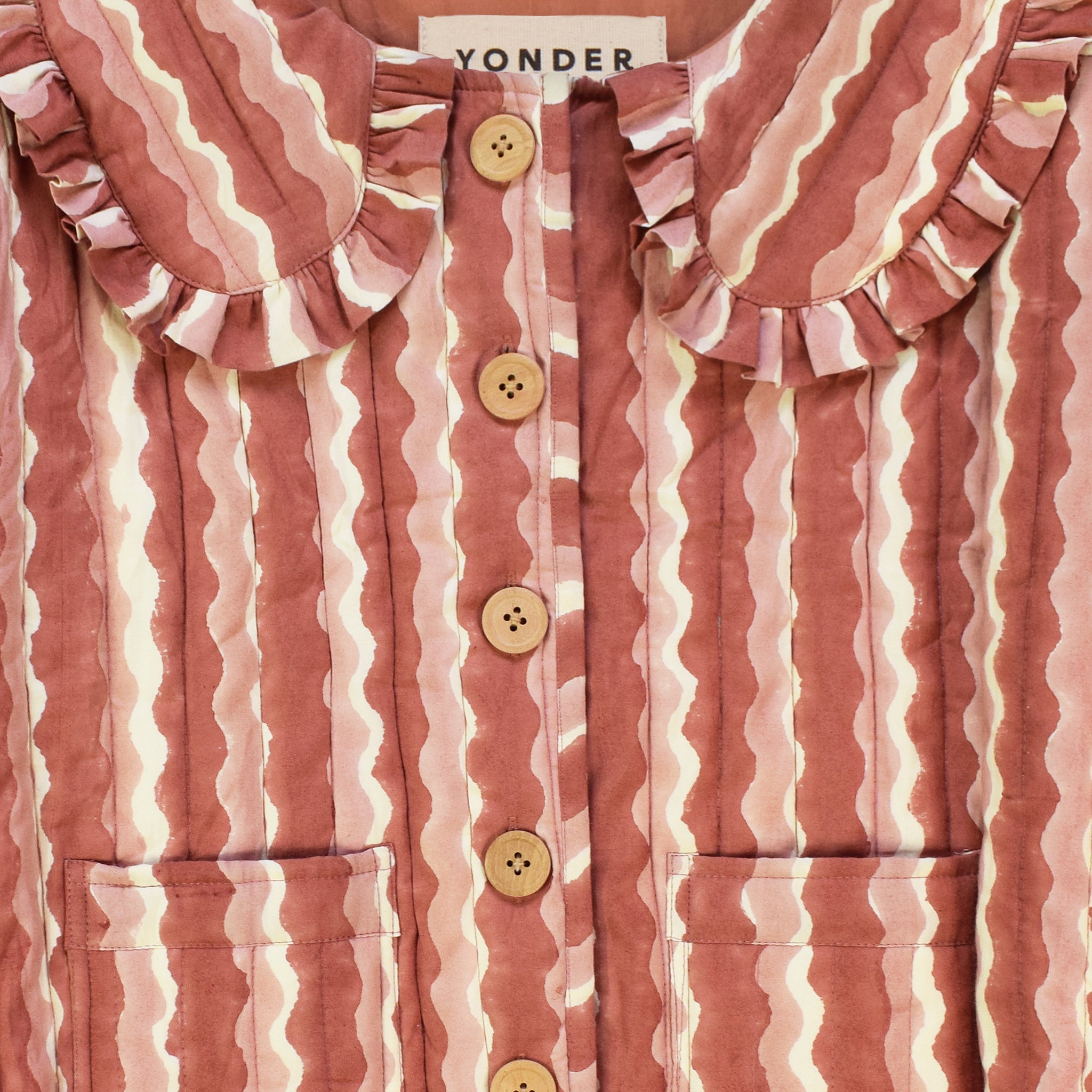 Closeup of cotton quilted jacket printed with pink striped wave pattern and frill collar