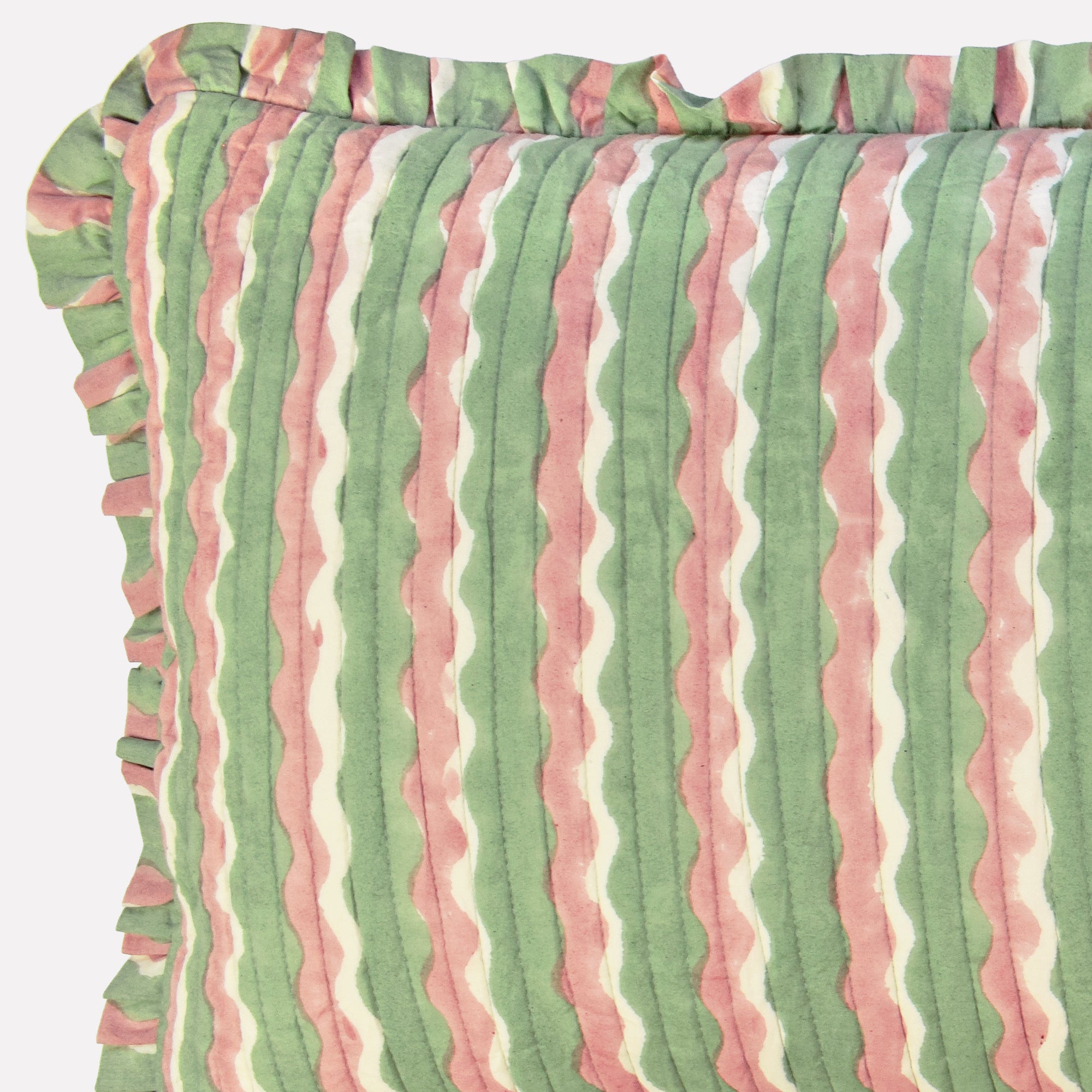 Closeup of long cotton quilted cushion printed with green and pink striped wave pattern and frill border