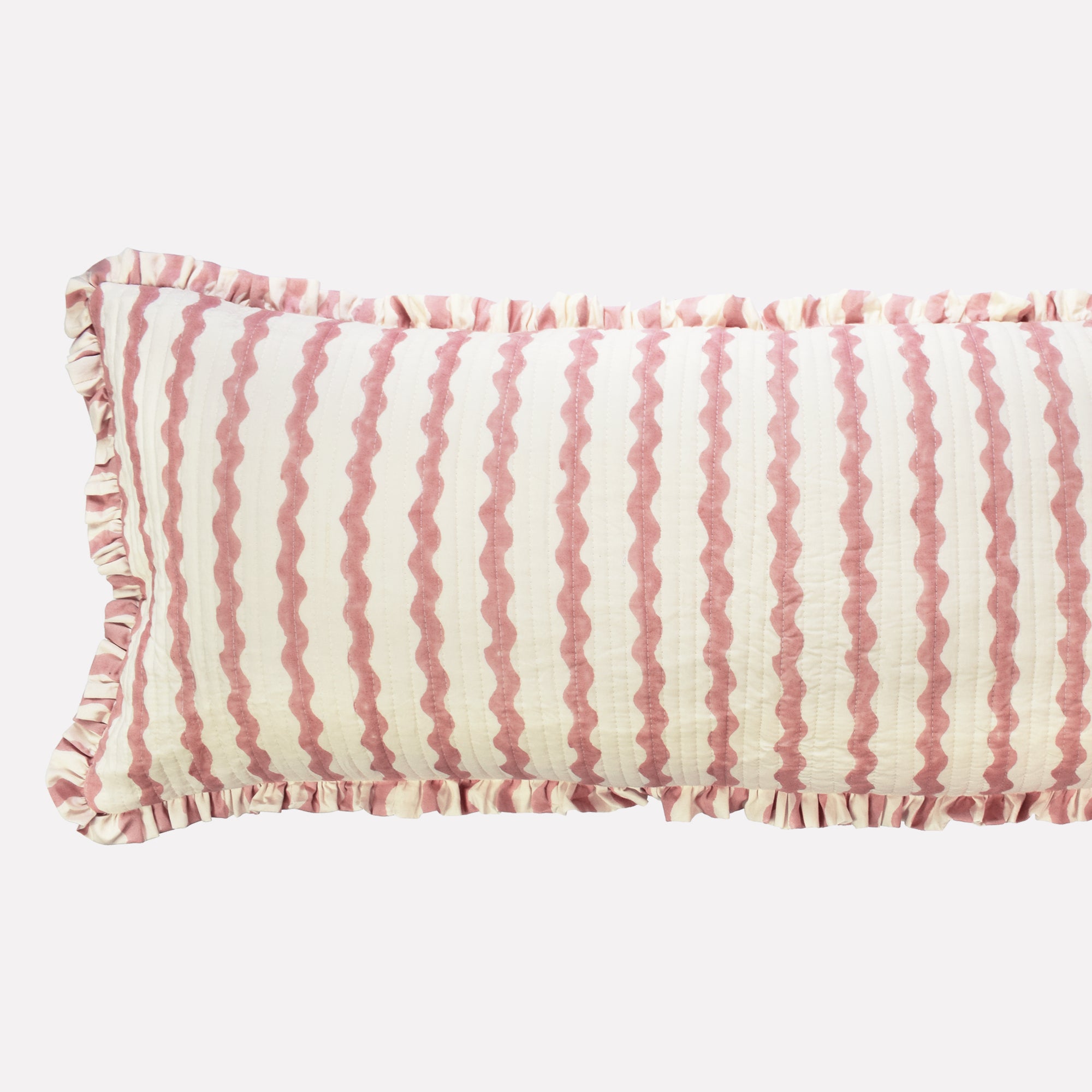 Closeup of long cotton quilted cushion printed with pink and white striped wave pattern and frill border